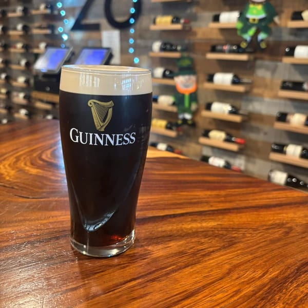 A pint of Guinness beer with a creamy head sits on a wooden bar at Barrel 28.