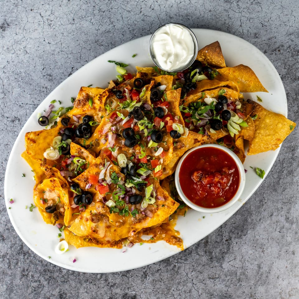 Barrel 28 nachos with melted cheese, black olives, tomatoes, onions, and salsa and sour cream.