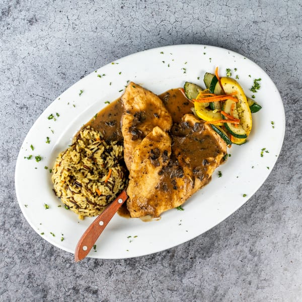 Barrel 28's chicken with mushroom sauce, wild rice, and mixed vegetables on a white plate.